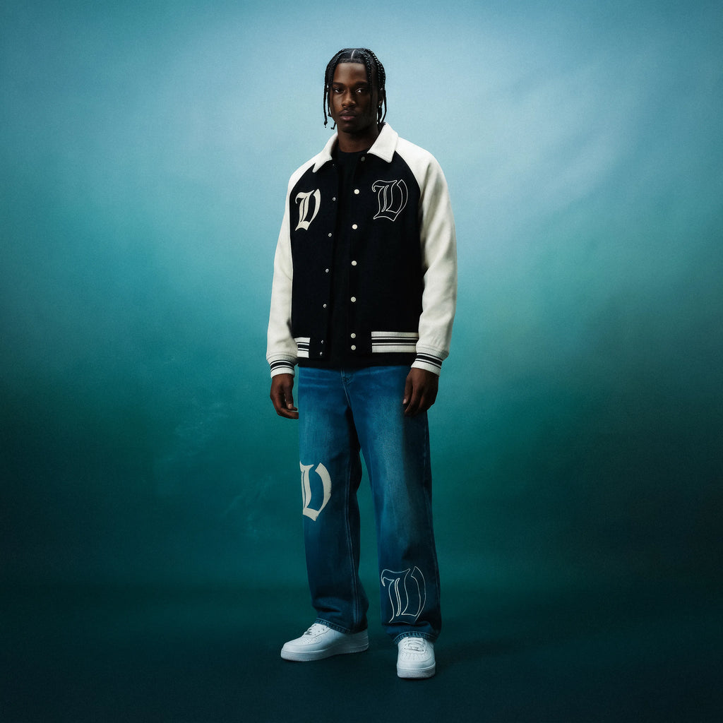 Person wearing a black and white varsity jacket by VENT D'HIVER with a blue background